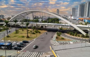 Imagem de ponte metálica, o Viaduto Reinaldo de Oliveira, em Osasco. Paisagem urbana em um dia de céu azul mostra a ponte, carros na avenida e prédios ao fundo