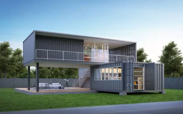 Imagem de uma casa container de dois andares com grandes janelas de vidro, um pátio aberto com assentos ao ar livre e cercada por grama e árvores.