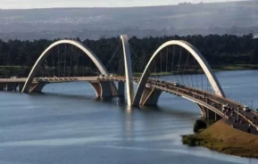 Imagem da Ponte JK, em Brasília, mostra o Lago Paranoá, carros atravessando a ponte e vegetação ao fundo em um dia de ceu azul para ilustrar matéria sobre o Lago Sul, em Brasília