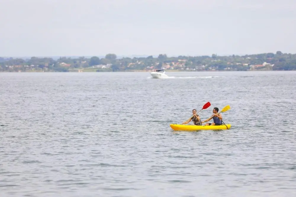 Imagem de duas pessoas remando um caiaque amarelo no Lago Paranoá para ilustrar matéria sobre o Lago Sul, em Brasília.