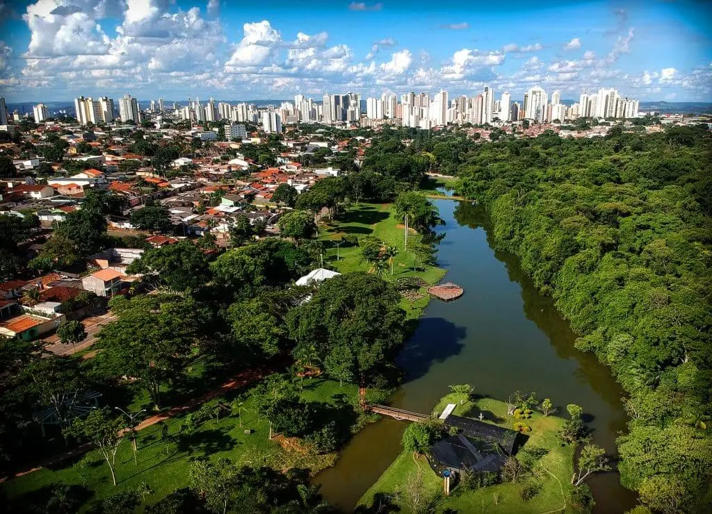 Imagem da vista aérea do Jardim Botânico de Goiânia mostra lago, vegetação, casas e prédios ao fundo para ilustrar matéria sobre os bairros mais baratos de Goiânia